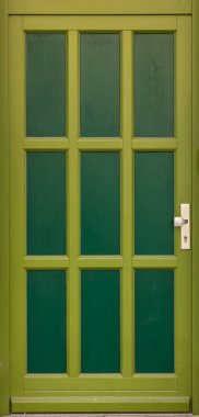 Yüksek dar panelli parlak kireç çerçeveli modern yeşil kapının dikey görüntüsü. Zengin gölgeler ve basit geometri şehrin ön cephesine taze bir ekolojik ilham getirir..