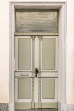 İnce detaylı ve ince kolonları olan çift pastel kapılar eski bir evin ön cephesinde duruyor. Sakin melodiler ve basit çizgiler girişte rahat bir his yaratır..