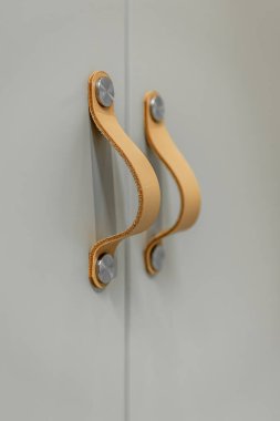 Tek bir deri kayış, hassas metal donanımlı bir mat cephesinde göze çarpıyor. Yumuşak ışık ve gölge iç mekanlar için yumuşak minimalizm ve temiz ayrıntı eğilimlerini destekler.