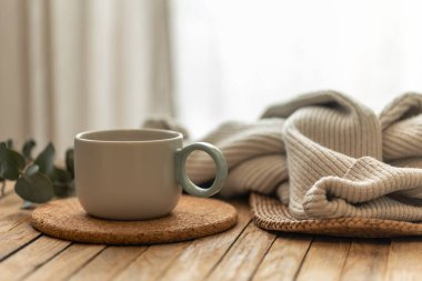 Mantar altlığı üzerinde asgari seramik bardak okaliptüs ve ahşap bir masanın üzerinde yumuşak örülü tekstil. Sakin bir iç mekan refahı uyduruyor yavaş yaşam ve hygge ilham verici yaşam tarzı içeriği.