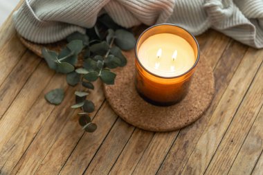 Yanında okaliptüs ve yumuşak örgü tekstil bulunan mantar altlığı üzerinde iki alevli mum. Yumuşak gün ışığı ve doğal dokular yavaş yavaş iyileşen refah ve bencillik için kızlık zarı havası verir..