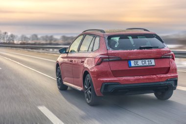 Sıcak akşam ışığında, karlı arazide asfalt yolda ilerleyen modern bir arazi aracı. Dinamik sahne, özgürlük, konfor ve seyahat yaşam tarzı kavramını taşır.