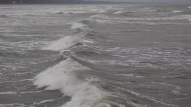 Aktif okyanus dalgaları karamsar atmosferdeki insansız hava aracının görüntüsünden elde edilen kıyı şeridi yakınlarında hareket eder ve kırılır. Seyahat, açık hava ve özgürlük konseptini gösteren sinematik doğa sahnesi.