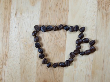 Kahve çekirdekleri kahve Kupası şekil üzerinde ahşap arka plan yapmak