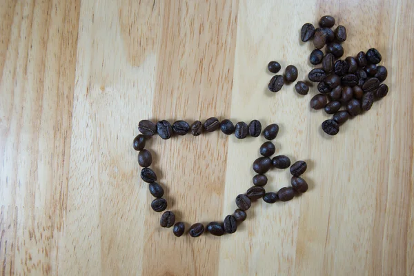 Grains de café font en forme de tasse de café sur fond de bois — Photo