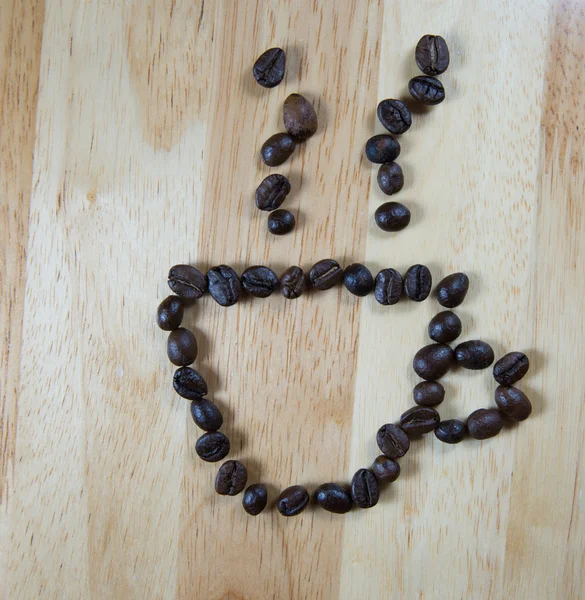 Szemes kávé, hogy a kávé csésze alakú fa háttér — Stock Fotó