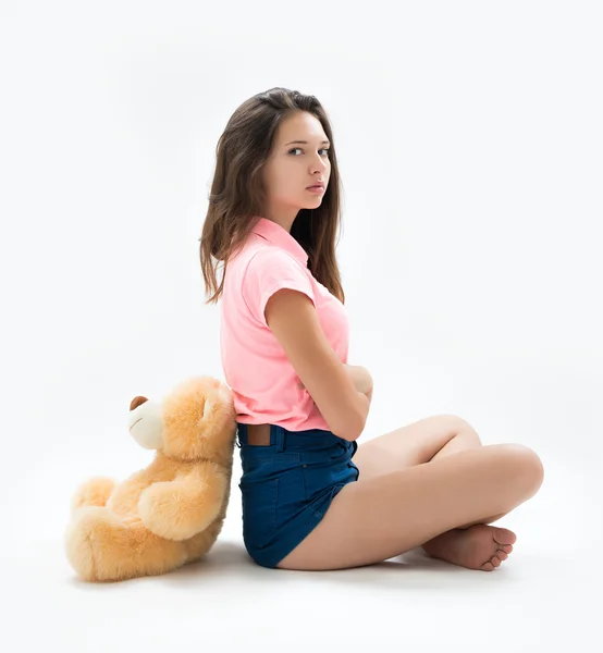 Portrait of a beautiful young brunette with a teddy bear in the studio — Stock Photo, Image