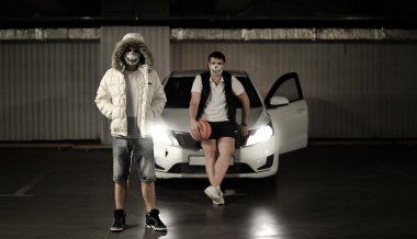 maskeleri bir basketbol ile arabanın yanındaki park yerinde iki adam portresi