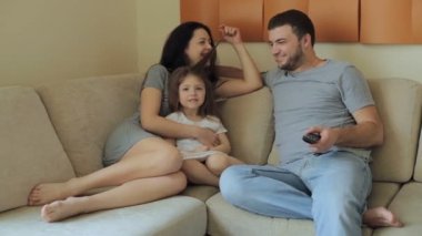 Genç aile kanepede oturup televizyon izlerken