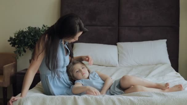 Madre peinando el pelo hija en la cama en casa — Vídeo de stock