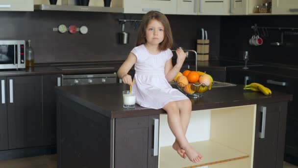 Маленькая девочка сидит на кухонном столе — стоковое видео