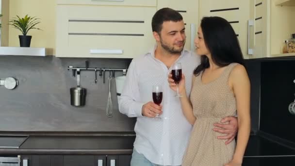 Pareja joven bebiendo vino tinto en la cocina en casa — Vídeos de Stock