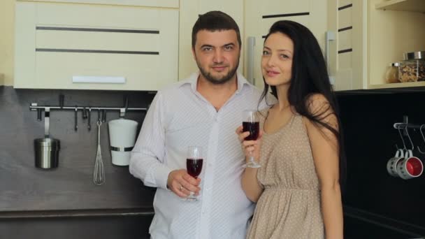 Pareja joven bebiendo vino tinto en la cocina en casa — Vídeos de Stock