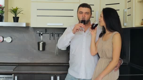 Pareja joven bebiendo vino tinto en la cocina en casa — Vídeos de Stock