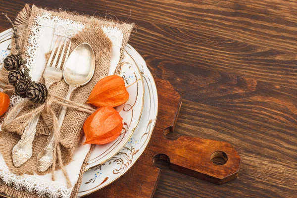 Servies met oranje Physalis en zilverwerk — Stockfoto