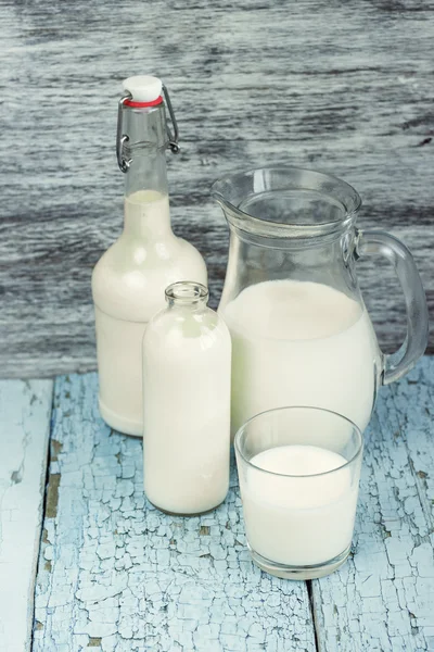 Jar and bottles with milk, and full glass with milk — Stock Photo, Image