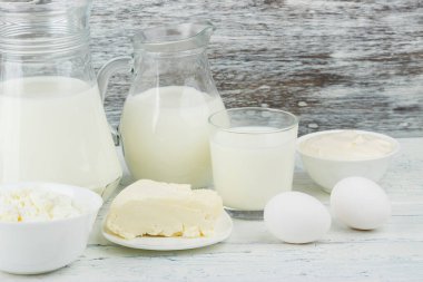 Beyaz tahta tahtalarda farklı süt ürünleri, bulanık arka plan.