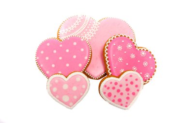 Pembe kurabiyelerin arka planında kalp farklı şekillerde, beyaz renkte izole edilmiş.