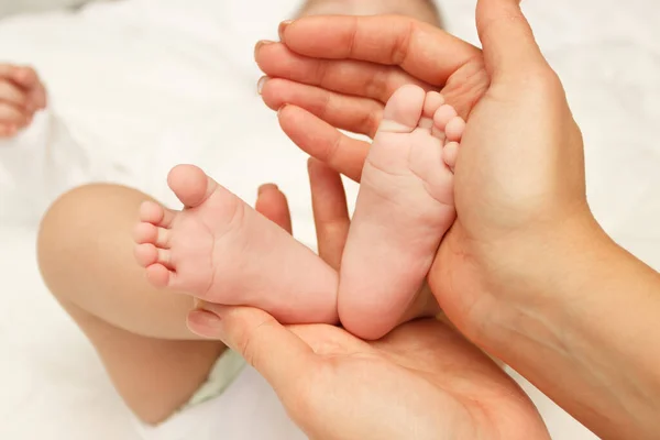 Las Manos Mujer Sostiene Los Pies Del Bebé Fondo Enfoque — Foto de Stock