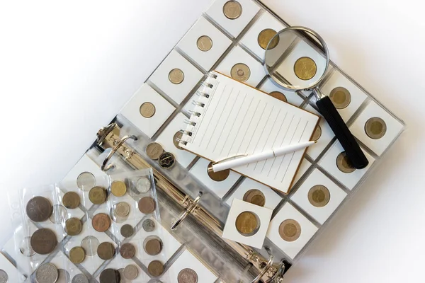 Different old collector's coins with a magnifying glass, blurred