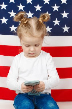 Amerikan Dollarsi 'si olan küçük güzel bir kız elleri, arka planda Amerikan Bayrağı