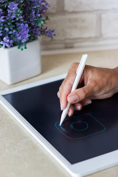 Woman drawing with a tablet device, soft focus background