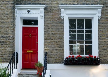 Kırmızı ve beyaz kapılı ve pencereli tuğla binanın ön cephesi