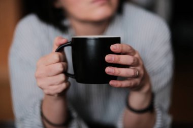 Kadın kahve bardağını kafede tutuyor.