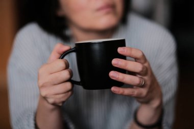 Kadın kahve bardağını kafede tutuyor.