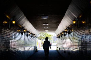 Karanlık bir yeraltı geçidinde yürüyen insanlar