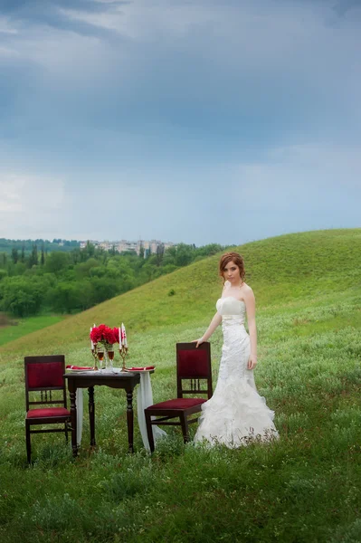 Mariée dans un champ près de la table de mariage servie — Photo