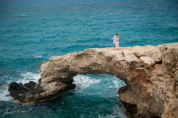 Par hålla händerna på en klippa mitt i havet — Stockfoto