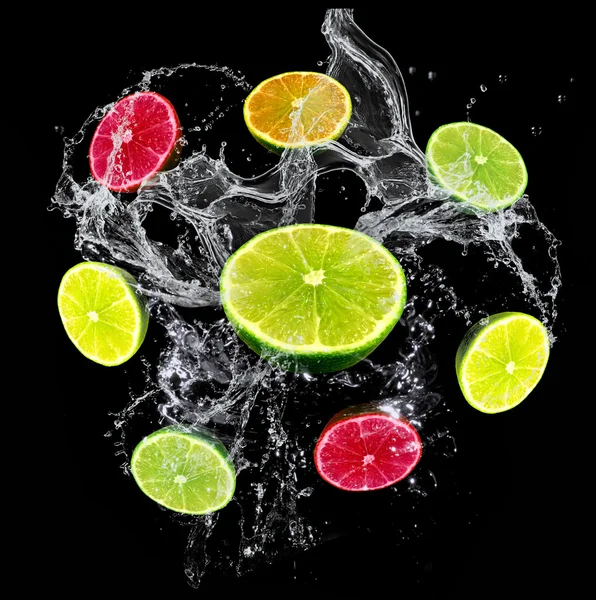 Gul, grön, orange, röda citrusfrukter (lime, grapefrukt, citron) på svart bakgrund med vattenstänk — Stockfoto
