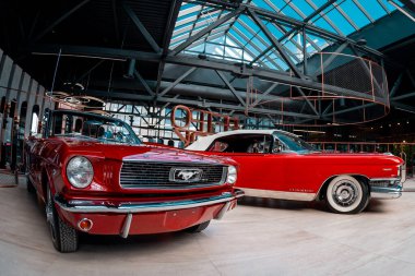Cherry ford Mustang ve kırmızı Codillac Eldorado 20 Nisan 2018 'de Novokuznetsk, Kemerovo Bölgesi, Rusya Federasyonu' ndaki Retro Arabalar Müzesi binasında..