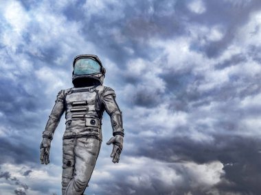 Uzay giysisi içindeki bir astronot bulutlu bir gökyüzüne karşı duruyor. Sahne, keşif ve teknoloji temalarını aktarıyor.