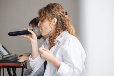 Bir konserde mikrofona kıvırcık saçlı beyaz bir kadın şarkı söylüyor. Bir adam yakınlarda oturuyor, sıcak bir aile ortamı yaratıyor..