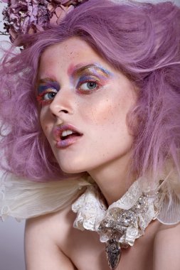 Kız parlak makyaj ve gerdanlık kolye ile. Mor saç.