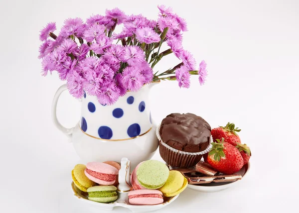 Macaroons üzerinde uçan daire ile Vazoda Çiçekler. Karanfil ve tatlılar.