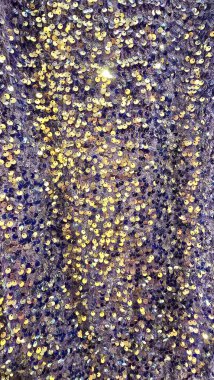 Altın ve mor pullarla süslenmiş ışıldayan bir kumaşın yakın çekimi. Bu canlı dokunun pırıl pırıl bir etkisi var. Tatil tasarımları, moda projeleri, reklam materyalleri, ambalajlar, afişler ve arka planlar için mükemmel.. 