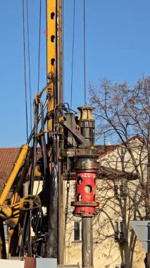 Güneşli bir günde bir inşaat alanında sondaj kulesi. Ekipman bileşenleri, metal kablolar, hidrolikler ve sondaj mekanizmasının yakın çekimleri. Sanayi teması: İnşaat, mühendislik ve ağır ekipman.