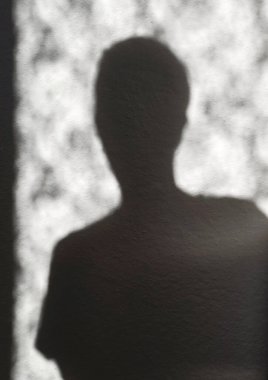 Dokulu bir duvardaki insan figürünün soyut gölge silueti. Anonimliği, kimliği, yalnızlığı, ruh sağlığını ve duygusal durumları temsil eden kavramsal bir imaj. Kopyalama alanı olan minimalist kompozisyon.