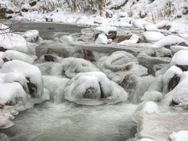 Dağlarda kış manzarası. Karla kaplı orman. Nehir karda akıyor..