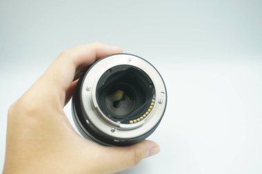 Beyaz arka planda mantar olmadan kameranın lensini ters çeviren bir el..