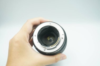 Beyaz arka planda mantar olmadan kameranın lensini ters çeviren bir el..