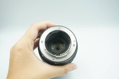 Beyaz arka planda mantar olmadan kameranın lensini ters çeviren bir el..