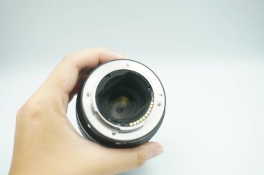 Beyaz arka planda mantar olmadan kameranın lensini ters çeviren bir el..
