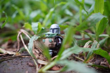 Yeşil çimlerin arasında duran mandalorian ve grogu 'nun (yıldız savaşları) küçük bir lego figürü..