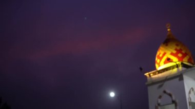 Sabahın erken saatlerinde cami kubbesindeki ışıklarla turuncu gökyüzü manzarası.