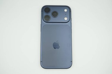 iPhone 17 Pro 'nun arkasında, koyu mavi bir varyant, üçlü kamera ve Apple logosu bulunur. iPhone beyaz bir arkaplanda oturuyor.
