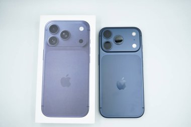 iPhone kutusu iPhone 17 Pro derin mavi varyantın yanındadır ve beyaz arkaplan ile baş aşağı.